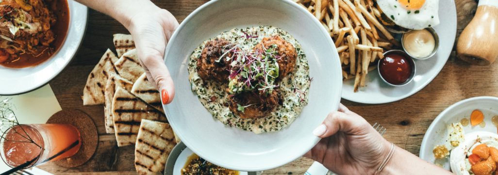 person holding white plate with food